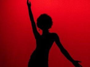 暗红色背景下舞者的剪影，左臂抬起